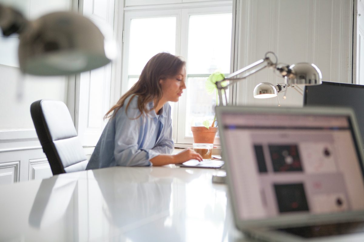 Woman at desk writing an article about 5 Reasons Why Your Website Isn't Booking Clients (And How to Fix Each Mistake)